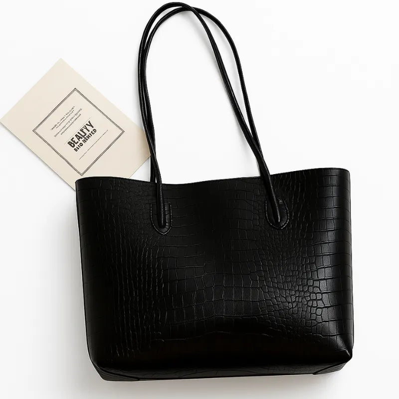 Bolsa tote preta de croco, vista frontal. A foto exibe o design do acessório e o punho duplo, pronto para compromissos e compras.