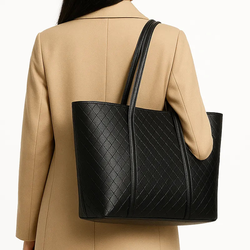 Modelo usando a bolsa tote preta, em vista lateral. A foto realça a praticidade do punho duplo e o caimento da bolsa ao corpo.