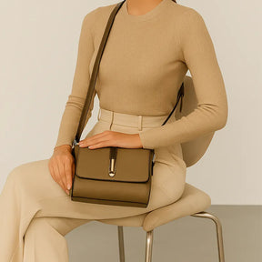Bolsa transversal bege Gusure Luxuosa sendo carregada por uma mulher em pose casual sentada, destacando praticidade