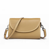 Bolsa transversal feminina bege de couro genuíno. Vista frontal em estúdio, destacando o design atemporal com aba arredondada, fechamento por zíper e alça ajustável.
