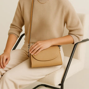 Mulher usando a Bolsa Transversal Stella Maris bege em um look casual elegante. A foto mostra o acessório a tiracolo, ideal para o dia a dia e para carregar itens essenciais.

