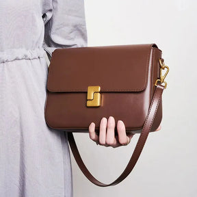 Modelo usando a bolsa transversal Prestige. A foto destaca a versatilidade do acessório, que pode ser usado a tiracolo ou na mão com alça curta.