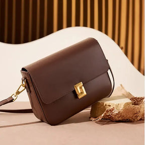 Detalhe da bolsa transversal de couro Prestige em um ambiente casual. A imagem foca na qualidade do couro e no fechamento elegante.