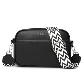 Bolsa transversal preta com alça listrada, vista frontal, destacando design moderno e couro genuíno