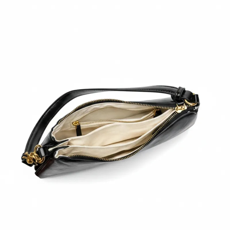 Bolsa baguete preta em vista frontal. A foto exibe a alça de ombro com detalhes metálicos em ouro velho.