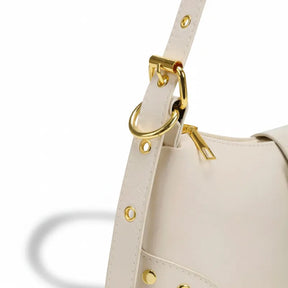 Detalhe da fivela e dos rebites dourados. A imagem em close aproxima os detalhes que dão um toque moderno e elegante à bolsa.