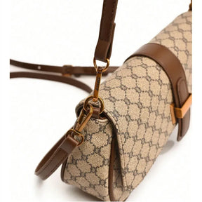 Bolsa de ombro bege com alca marrom. A imagem em close realça o formato cilíndrico e o acabamento em couro nas laterais.