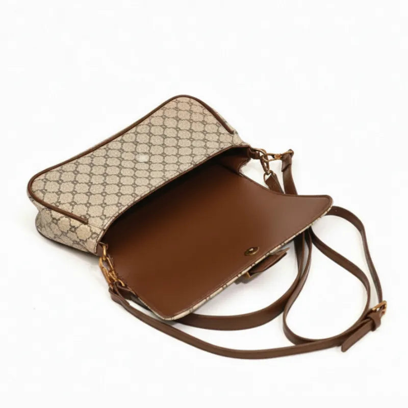 Vista superior da bolsa de ombro bege aberta. A foto revela o interior e o mecanismo do fecho de barra metalico.