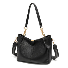 Bolsa hobo preta com corrente dourada em close no fecho e nas ferragens, com textura e brilho em destaque