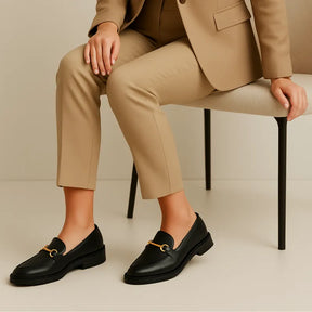 Loafer preto feminino com fivela sendo usado por uma mulher em pé com pose casual, destacando versatilidade