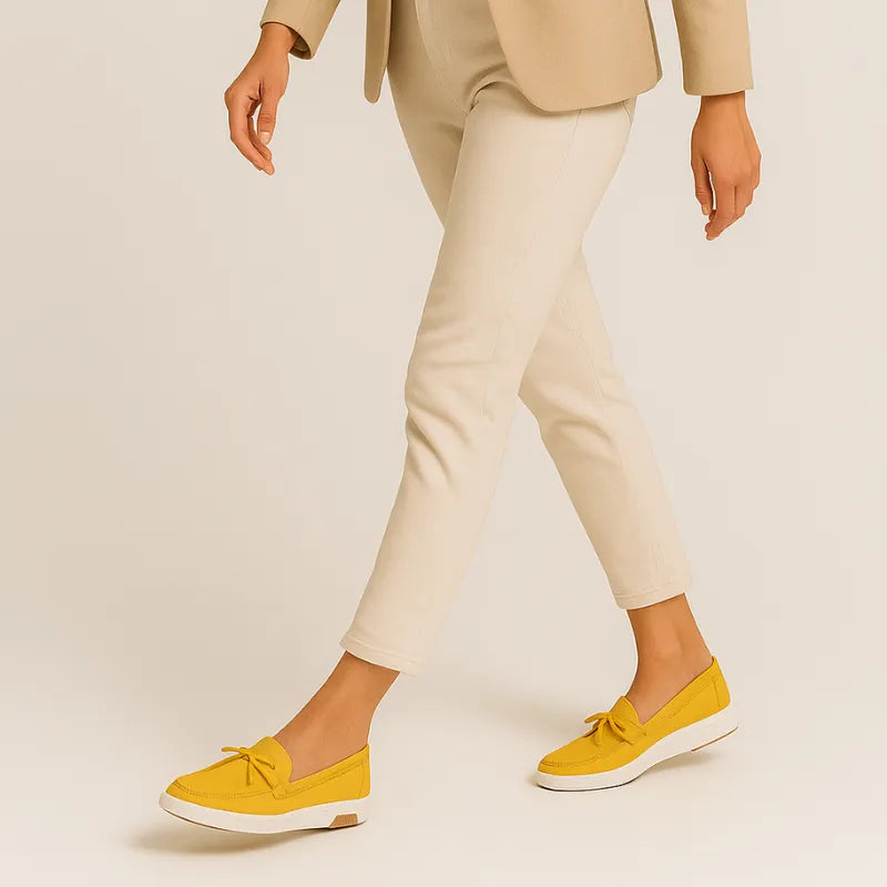 Mocassim amarelo com laço sendo usado por uma mulher em pé com pose casual, mostrando conforto.