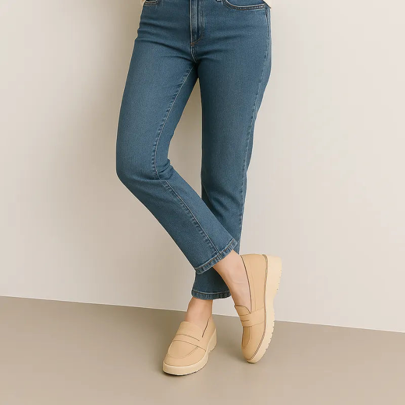 Mocassim bege clássico em couro sendo usado por uma mulher em pé com pose casual, mostrando conforto.
