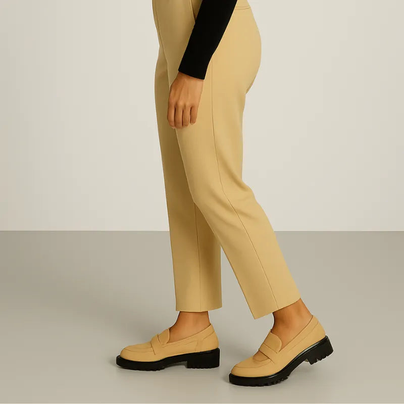 Modelo usando o mocassim Vittoria Cielo da Rozze, em pé. A foto mostra o calçado em uso, complementando um look casual e elegante com calça bege.