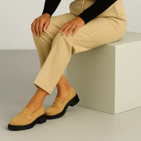 Modelo usando o mocassim Vittoria Cielo da Rozze, sentado. A imagem realça a praticidade e o conforto do calçado para o dia a dia.