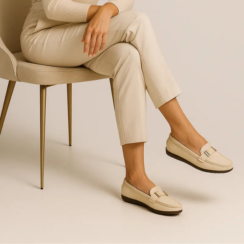 Modelo usando o mocassim branco de couro da Rozze, sentada. A imagem mostra o calçado em uso, complementando um look casual e confortável.