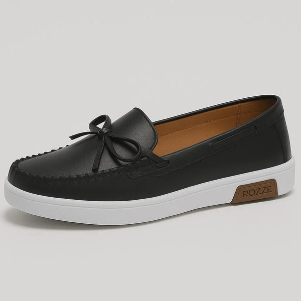 Mocassim preto com laço, vista frontal, destacando design moderno com laço decorativo e sola antiderrapante