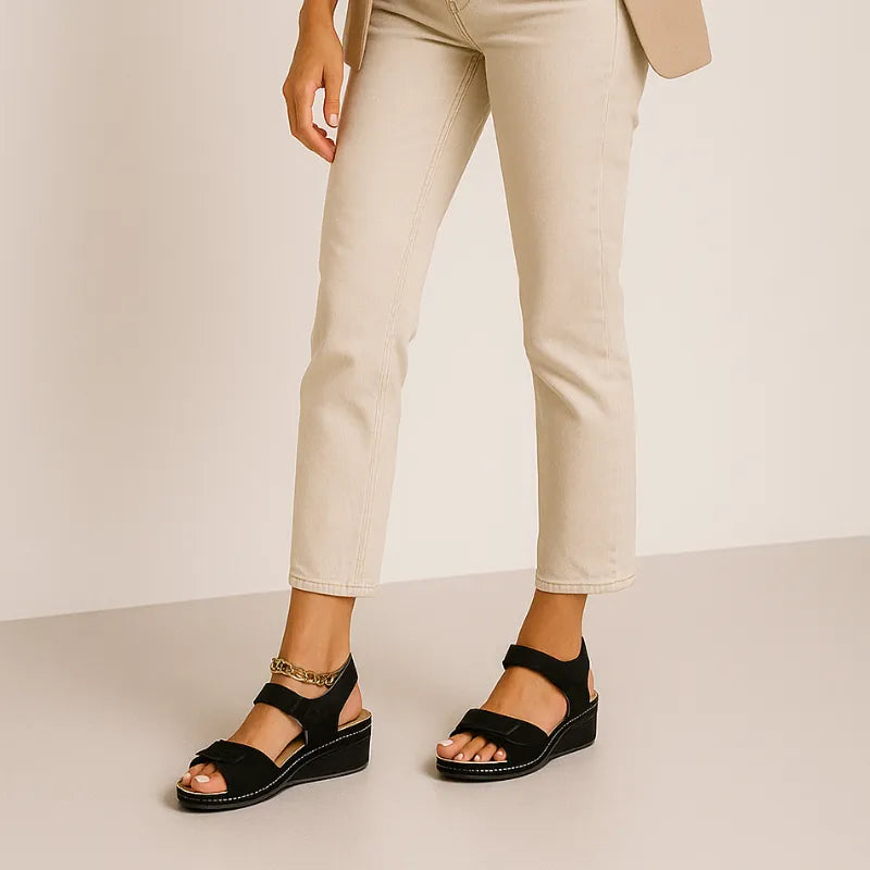 Modelo usando a sandália plataforma preta Josette, em pé. A imagem mostra o calçado em uso, complementando um look casual com calça clara.