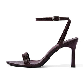 Sandália feminina vinho de salto agulha, vista lateral em estúdio. A foto destaca a estampa croco, a tira no tornozelo e o salto de 9 cm.