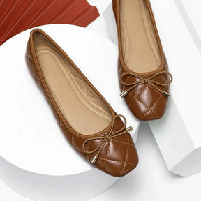 Par de sapatilhas marrons acolchoadas com laço da Rozze, em um close. A imagem realça a versatilidade do calçado para looks casuais e elegantes.