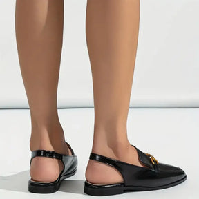 Modelo usando a sapatilha preta slingback da Rozze, em uma pose de perfil. A foto realça a praticidade do calçado e a sua versatilidade para o dia a dia.