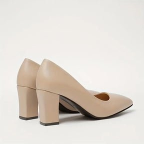 Par de scarpins salto bloco beige bico fino sobre fundo claro, destacando solado de borracha.
