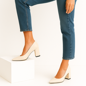 Modelo em pé com o scarpin branco sobre um bloco. A imagem enfatiza o conforto e a estabilidade do salto bloco para uso prolongado.