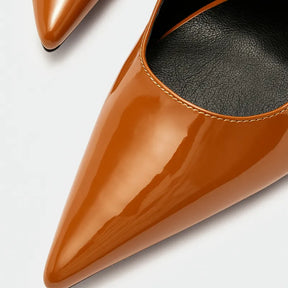 Vista traseira do scarpin castanho de verniz da Rozze. A imagem em close detalha a sola preta e o acabamento do salto agulha, mostrando a qualidade do produto.