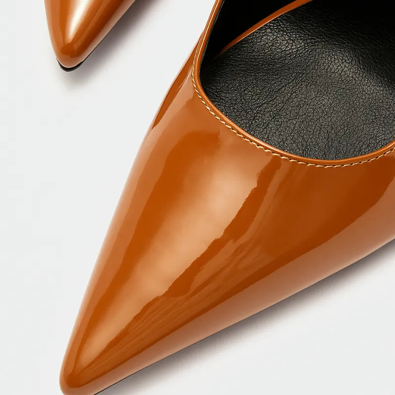 Vista traseira do scarpin castanho de verniz da Rozze. A imagem em close detalha a sola preta e o acabamento do salto agulha, mostrando a qualidade do produto.