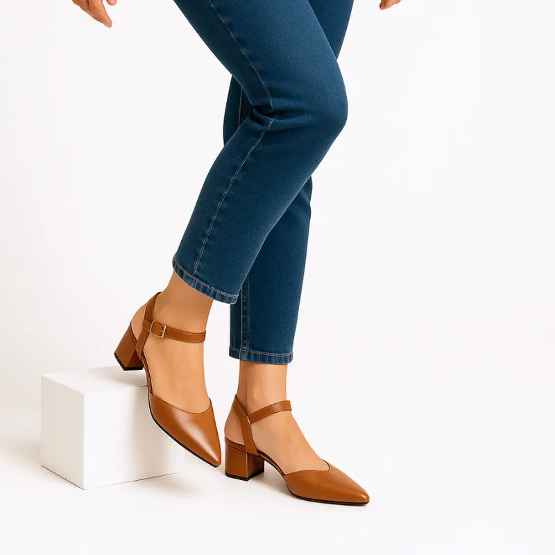 Vista de perfil da modelo usando o scarpin marrom com salto bloco da Rozze. A foto realça a silhueta do calçado no pé, combinando com calça jeans de barra dobrada.