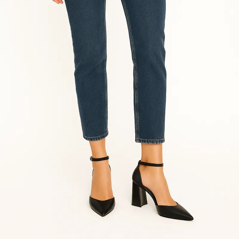 Modelo usando o scarpin preto com tira no tornozelo da Rozze, em pé. A foto de perfil enfatiza a estabilidade e a altura do salto chunky de 9 cm, ideal para o dia a dia e ocasiões sociais.