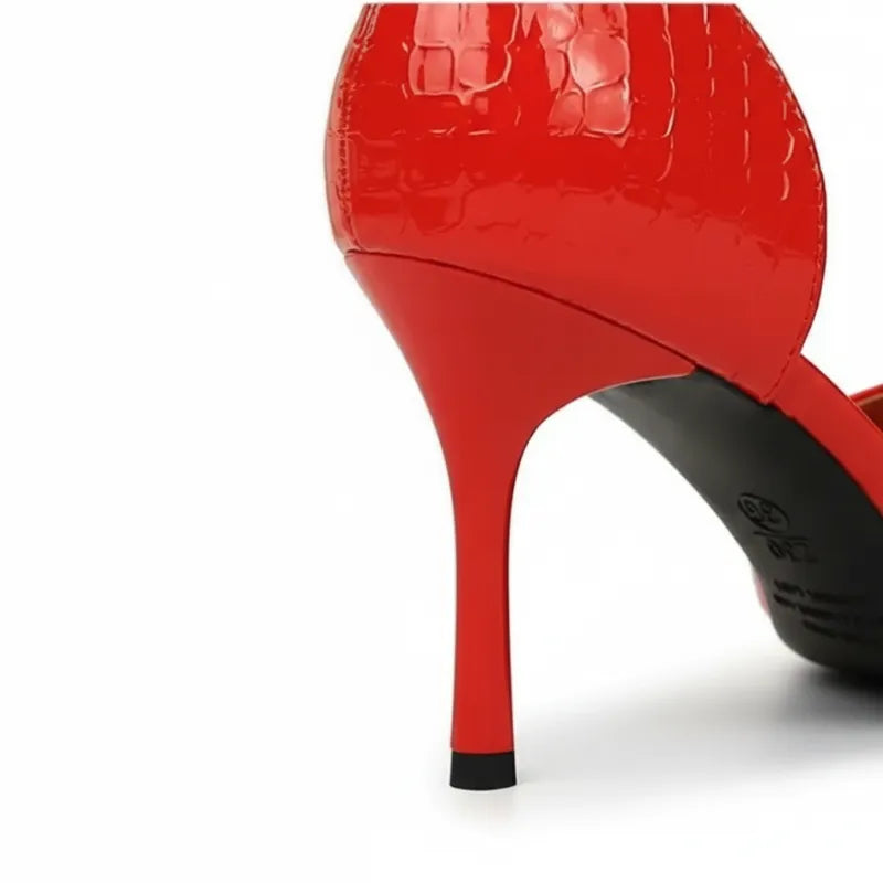 Detalhe do calcanhar do scarpin vermelho. A foto em close mostra a textura croco em relevo e a estrutura do salto.