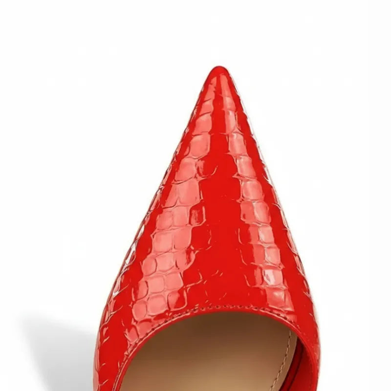 Vista superior do bico do scarpin vermelho. A imagem foca na qualidade do material verniz e na sofisticação da textura animal print.
