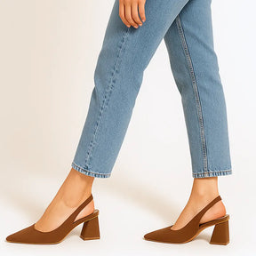Modelo usando o scarpin slingback marrom da Rozze, em pé. A foto de perfil enfatiza a estabilidade e a altura do salto bloco para uso prolongado.