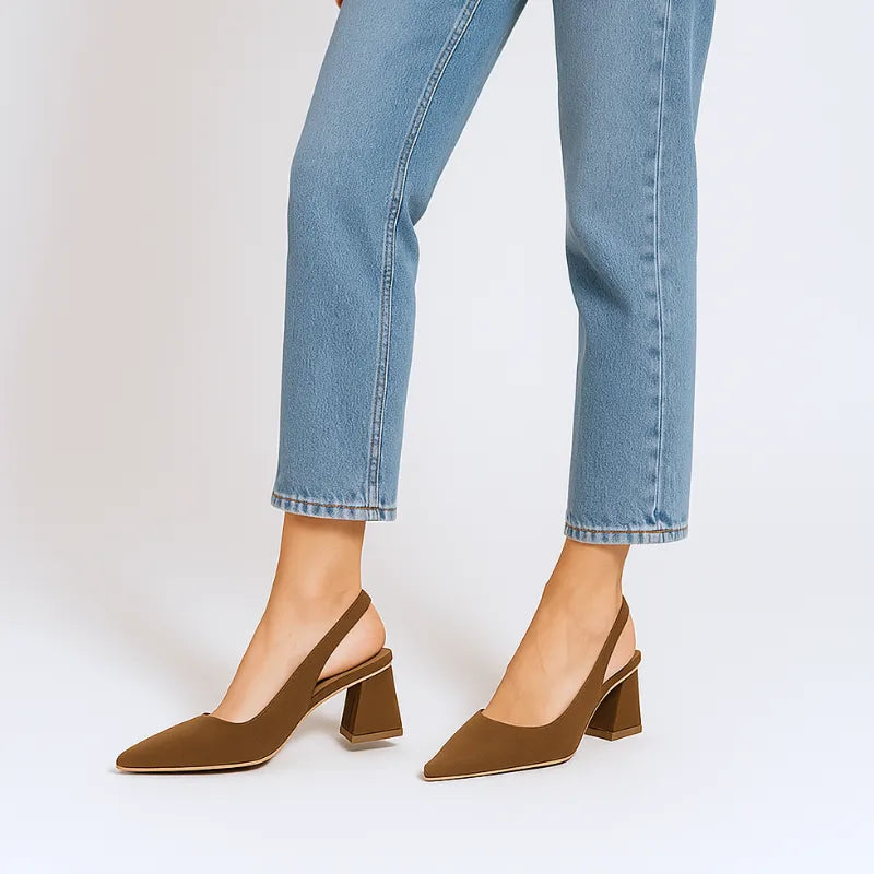Vista de perfil da modelo usando o scarpin slingback marrom da Rozze. A foto realça a silhueta do calçado no pé, combinando com calça jeans de barra dobrada.