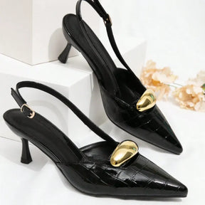 Par de scarpins pretos com detalhe dourado. A imagem realça a elegância do calçado, mostrando a fivela metálica e a tira slingback.