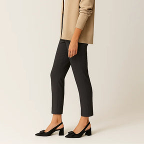 Modelo usando o scarpin slingback preto com laço da Rozze, em pé. A foto de perfil enfatiza a estabilidade e o conforto do salto chunky para o uso diário.