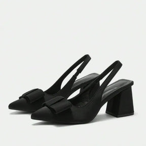 Par de scarpins slingback pretos com laço da Rozze, em vista de ângulo. A foto em estúdio destaca o design moderno, o salto chunky e a forma do calçado.