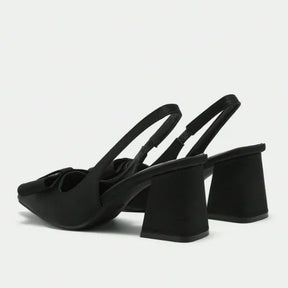 Par de scarpins slingback pretos com laço da Rozze, em vista de frente e de trás. A foto exibe a tira traseira, o laço elegante e a forma do calçado.