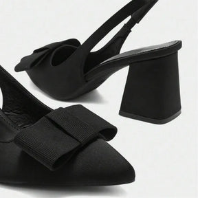 Detalhe do laço e da ponta do scarpin slingback preto. A foto realça o laço decorativo e o bico fino elegante do calçado.