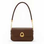 Bolsa baguete marrom fecho metálico dourado em vista frontal, com alça trançada, formato compacto e estrutura visível