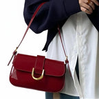 Bolsa baguete vermelho verniz fivela dourada usada no ombro pela modelo, mostrando proporção e caimento frontal