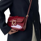 Bolsa baguete vermelho verniz fivela dourada usada pela modelo em vista lateral, com caimento e ajuste da alça