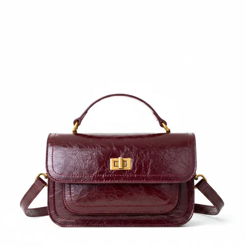Bolsa crossbody feminina couro vinho em vista frontal, com formato, alça e ferragens visíveis, sobre fundo claro