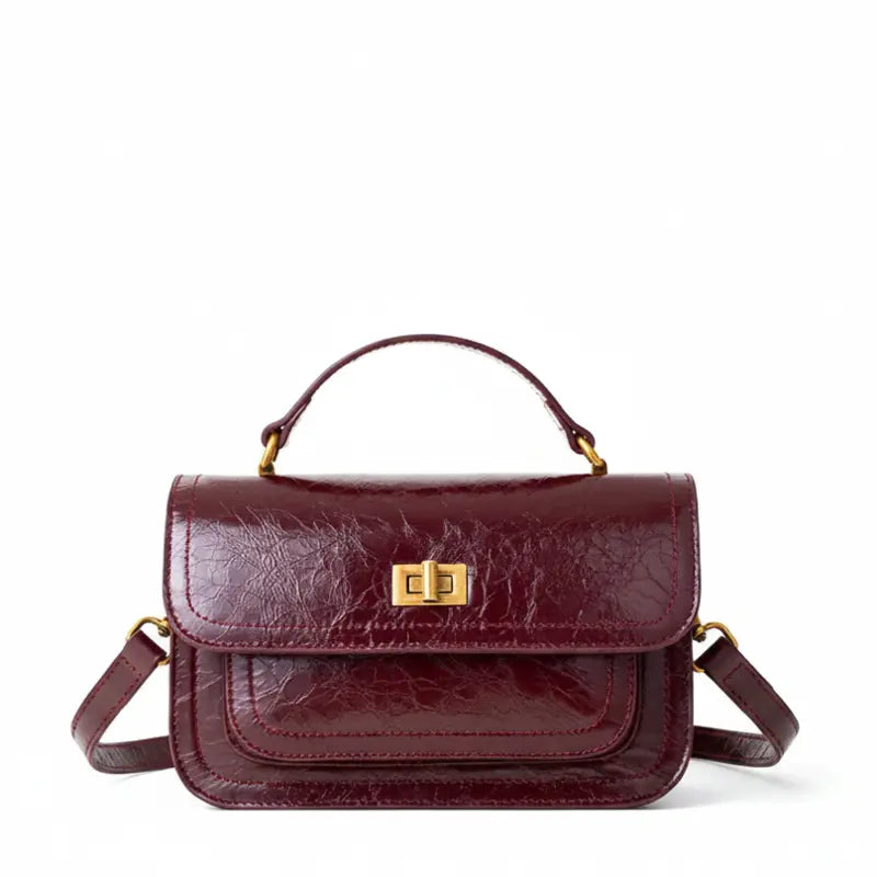 Bolsa crossbody feminina couro vinho em vista frontal, com formato, alça e ferragens visíveis, sobre fundo claro