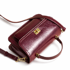 Bolsa crossbody feminina couro vinho em vista lateral, com profundidade, alça e acabamento visíveis, sobre fundo claro