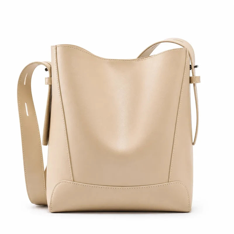 Bolsa de ombro bege em couro legítimo em vista frontal, destacando formato, alça larga e acabamento do couro.