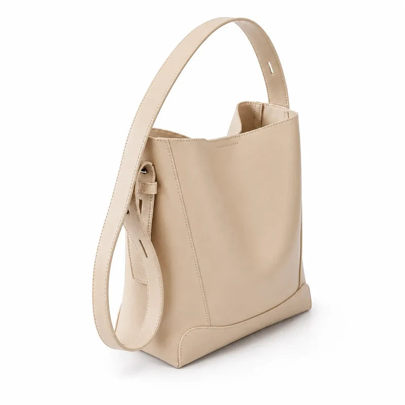 Bolsa de ombro bege em couro legítimo em vista lateral, mostrando profundidade, caimento e estrutura.