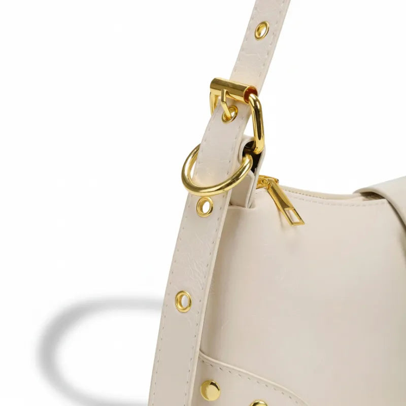 Bolsa de ombro branca com fivela dourada em close no fecho e nas ferragens, com textura e brilho em destaque