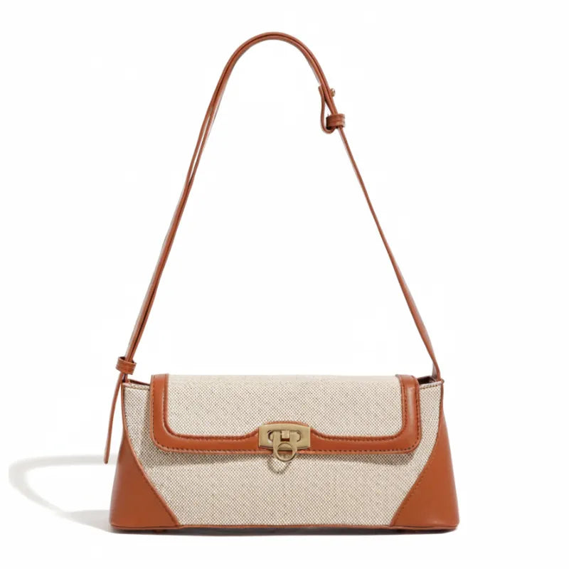 Bolsa de ombro marrom canvas trava dourada em vista frontal, com formato, alça e ferragens visíveis, sobre fundo claro
