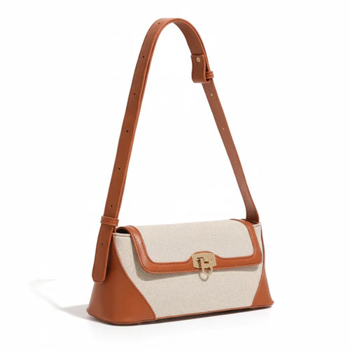 Bolsa de ombro marrom canvas trava dourada em vista lateral, com profundidade, alça e acabamento visíveis